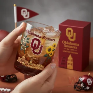 Oklahoma Sooners Limited Edition Whiskey Glass 3 Hands holding an Oklahoma Sooners whiskey glass with amber drink ice cubes in a cozy indoor team themed setting!