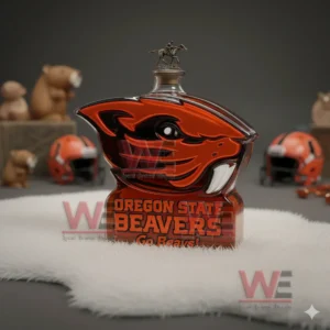 A beaver shaped orange and black bottle with Oregon State Beavers text standing on a white furry surface with helmets and small figures blurred in the background!