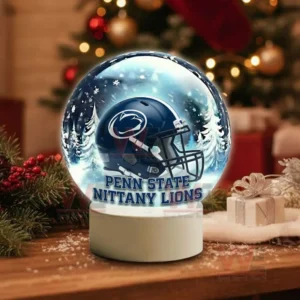 A snow globe with a dark blue team helmet sits on a wooden table with holiday decorations around it!