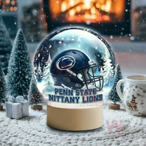A snow globe with a dark blue team helmet sits on snowy ground with winter trees around it!