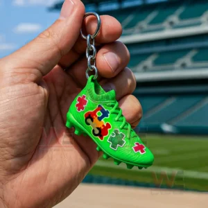 A green cleat keychain with colorful puzzle pieces held in front of a stadium!