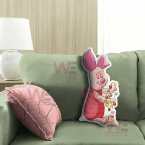 Pink pig character pillow with christmas lights placed on a green sofa in a warm living room!