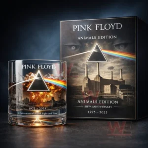 Pink Floyd Animals Edition whiskey glass with amber drink and ice placed beside a matching anniversary box with prism rainbow beam and industrial skyline artwork on a dark background.