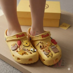 Pooh Crocs Clogs with Charms 4 Feet wearing yellow Pooh clogs decorated with honey themed charms and Pooh character designs.