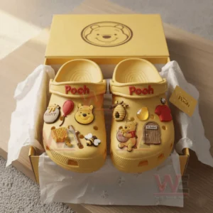 Pooh Crocs Clogs with Charms 5 Yellow Pooh clogs in a gift box decorated with charms shaped like honey pots balloons bees a hive a wooden door and Pooh character figures.