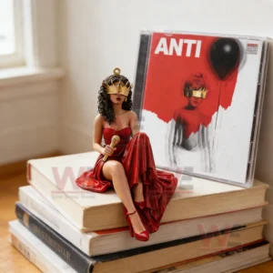Singer figurine in a red dress sitting on stacked books beside an Anti album case in a bright room!