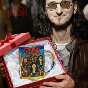 A stained style mug with band artwork resting in a red gift box held by a man wearing glasses with warm lights behind him!