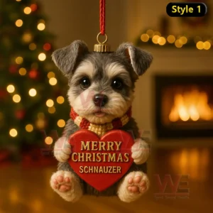 Schnauzer puppy holding a red Merry Christmas Schnauzer heart ornament indoors with warm festive lighting and a glowing fireplace!