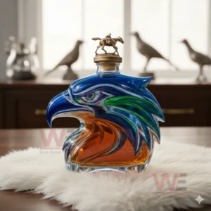 A multicolored eagle shaped whiskey bottle with rider cap on white fur with bird statues behind it.