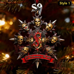 A metal ornament with sculpted masks and a central red symbol displayed among Christmas tree branches and glowing lights!