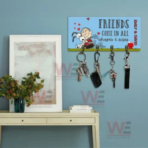 Friends come in all shapes and sizes key holder plaque with Emily and David names and four hooks holding keys displayed on a blue wall above a console table.