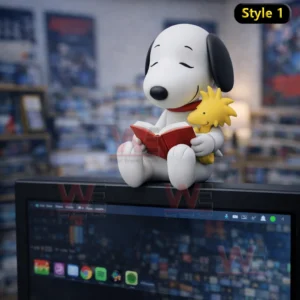 Snoopy desk figure reading a book while holding Woodstock sitting on top of a monitor in a cozy room!
