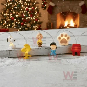 Snoopy themed string lights displayed on a snowy wooden surface with character figures and glowing decorations in a holiday room!