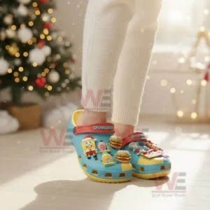 Person wearing Spongebob themed clogs with festive charms in a holiday decorated room!