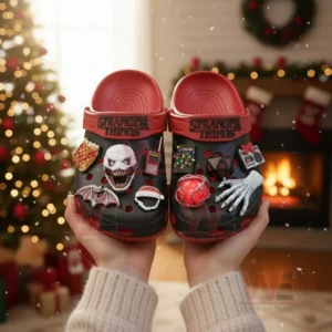 Hands holding black and red Stranger Things clogs decorated with themed charms in a festive room!