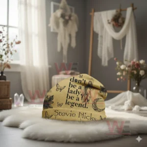 Yellow Stevie Nicks beanie with inspirational text and butterfly graphics on a white rug.