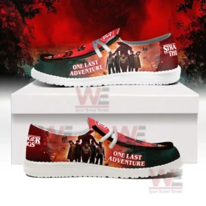 Stranger Things Hey Dude Shoes 9 Side view of Stranger Things shoes with character art and One Last Adventure text placed atop a white display box!