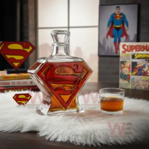 Superman symbol shaped bottle filled with amber drink sitting on a white rug next to a glass and comic decorations!