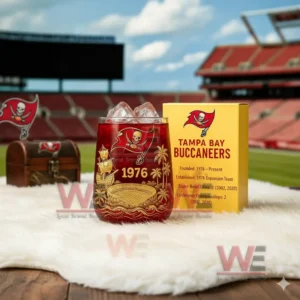 A red Buccaneers glass with detailed gold graphics next to a yellow box set against a football field backdrop!