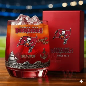 Tampa Bay Buccaneers whiskey glass with ice and red packaging standing on a wooden surface with a blurred football stadium background!