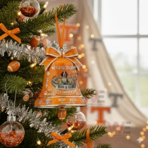 An orange stadium themed bell ornament with a dog mascot hanging on a Christmas tree among festive lights and decorations!