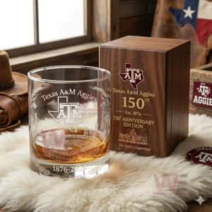 Texas A&M Aggies 150th Anniversary 1876-2026 Whiskey Glass 4 A Texas A M Aggies anniversary glass positioned near a wooden box on a soft surface in a warm rustic setting!