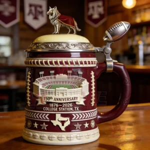 A decorative college anniversary beer stein with a stadium design mascot lid and ornate details placed on a wooden table!