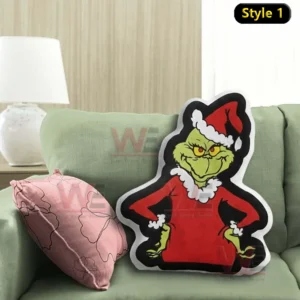 Green Grinch Santa character pillow displayed on a green sofa with a pink accent cushion in a warm living room setting!