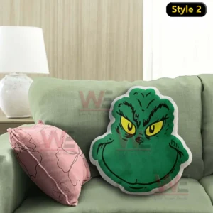 Close view of a green Grinch face pillow with yellow eyes resting against a green sofa cushion!