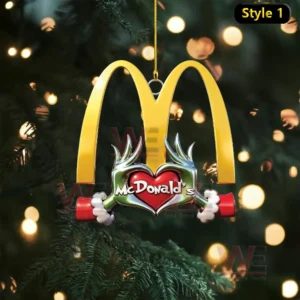 A golden McDonalds arch ornament with a red heart design hangs against a glowing Christmas tree backdrop!