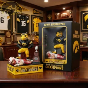 Iowa Hawkeyes mascot figure on a champions base standing over a defeated opponent with a small trophy and an Iowa Hawkeyes display box in a memorabilia room.
