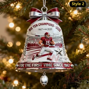 A detailed bell ornament showing a football player and stadium elements hanging on a lit Christmas tree!