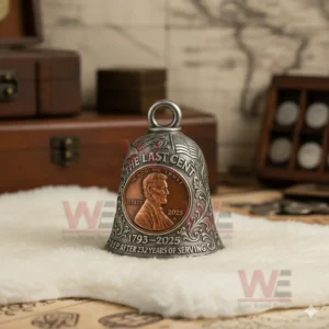 Metal commemorative bell with an American penny centerpiece celebrating the final cent and historical legacy displayed on a white cloth with vintage decor!