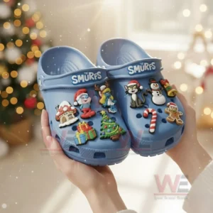 Hands holding light blue Smurfs clogs with festive character charms in a holiday setting!