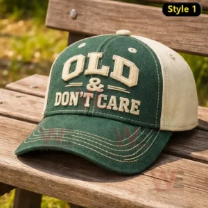 Green and cream baseball cap with raised embroidery reading Old and Dont Care resting on a wooden bench with a blurred outdoor background.