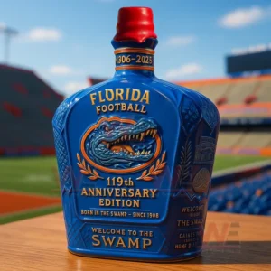 Blue Florida Football one hundred nineteenth anniversary edition bottle with an embossed gator emblem and Welcome to the Swamp text on a wooden table in front of a stadium.