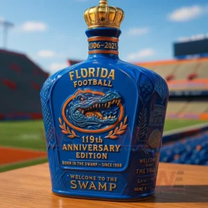 UF Football Florida Gators 119th Anniversary Edition Whiskey Bottle 6 Blue Florida Football one hundred nineteenth anniversary edition bottle with a gold crown topper and embossed gator emblem on a wooden table in front of a stadium.
