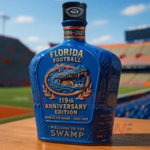 UF Football Florida Gators 119th Anniversary Edition Whiskey Bottle 7 Blue Florida Football one hundred nineteenth anniversary edition bottle with an Old No seven cap and embossed gator emblem displayed on a wooden table with a stadium background.