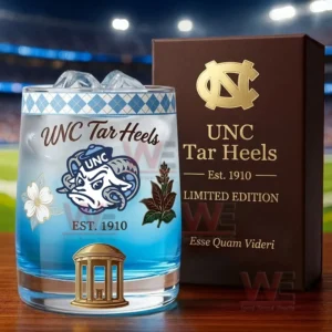 UNC Tar Heels whiskey glass with blue drink and ice next to a brown collector box featuring team logo and limited edition style on a wooden table in a stadium environment!