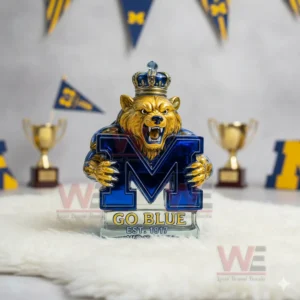 A crowned bear statue holding a blue M emblem set before Michigan themed flags and trophies!