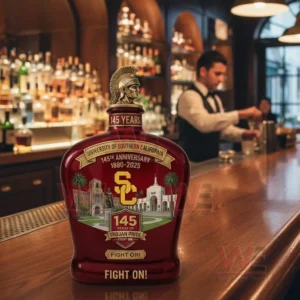 University Of Southern California USC 145Th Anniversary Fight On Whiskey Bottle 4 USC commemorative whiskey bottle with Trojan helmet topper one hundred forty five years anniversary label eighteen eighty to two thousand twenty five USC initials campus building illustrations and Fight On slogan shown on a bar counter with a bartender and liquor shelves behind!