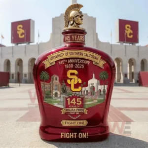 University Of Southern California USC 145Th Anniversary Fight On Whiskey Bottle 5 USC commemorative whiskey bottle with Trojan helmet topper one hundred forty five years text eighteen eighty to two thousand twenty five anniversary label USC initials landmark illustrations and Fight On slogan displayed outdoors in front of a stadium entrance with USC signage!