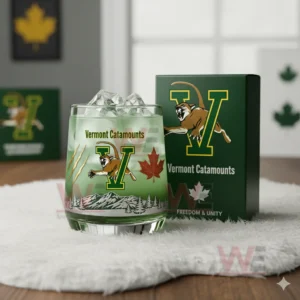 Vermont Catamounts whiskey glass with ice on a white fur surface next to a green branded box in a minimalist indoor environment!