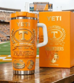 Orange Tennessee Volunteers Yeti tumbler with white handle and straw next to a matching orange box on a wooden table with a football stadium in the background!