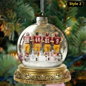 A glass globe ornament containing a coach and three Washington football icons walking forward together in a snowy holiday scene!