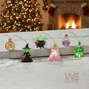 Wicked themed string lights displayed on a snowy wooden surface with character figures magical items and glowing decorations in a holiday setting!