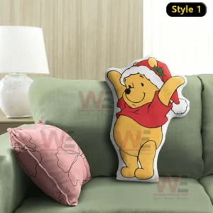 Christmas themed yellow bear pillow wearing a Santa hat resting on a green sofa beside a pink accent cushion in a calm home setting!