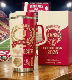 A red and cream Indiana Hoosiers championship tumbler for the undefeated 2026 national champions positioned on a wooden surface with a packed football stadium behind it!