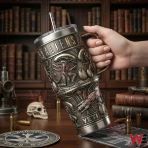 A hand holding an Aliens insulated tumbler above a desk with books props and science fiction themed objects!