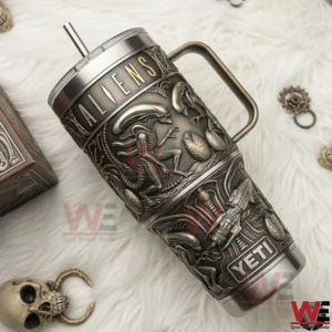 An Aliens insulated tumbler placed on a textured surface with decorative skull and accessories nearby!